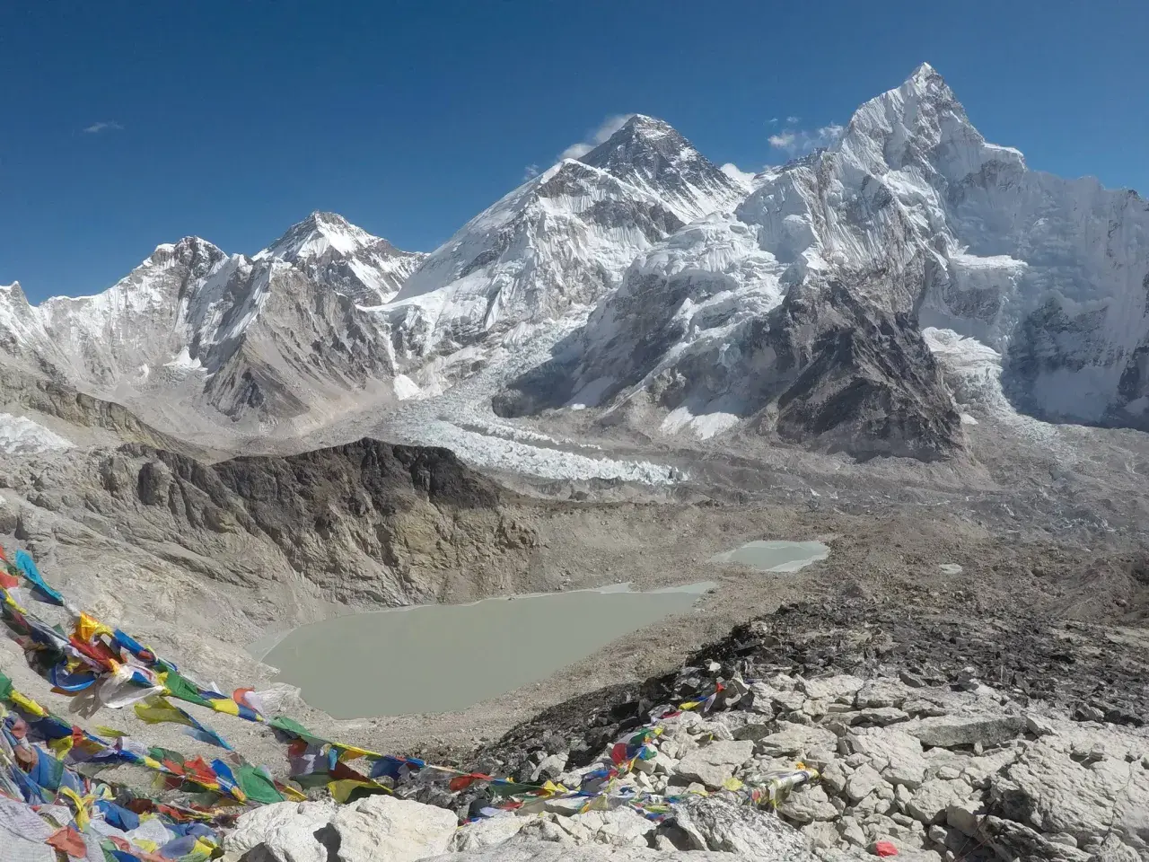 Bunte Gebetsfahnen wehen vor der majestätischen Kulisse des Kala Patthar mit dem Everest im Hintergrund.