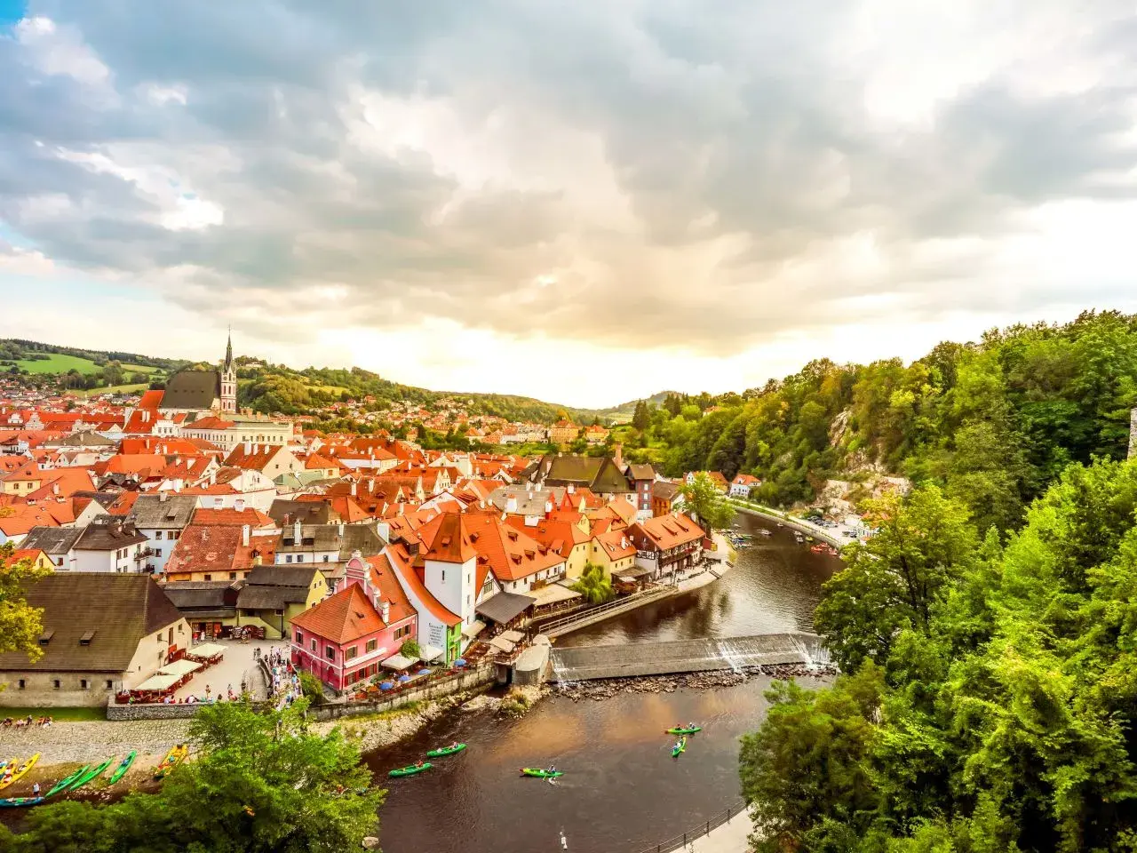 Malerische Stadt Český Krumlov, ein beliebtes Ausflugsziel in Tschechien, mit roten Dächern, Fluss und grünen Hügeln.
