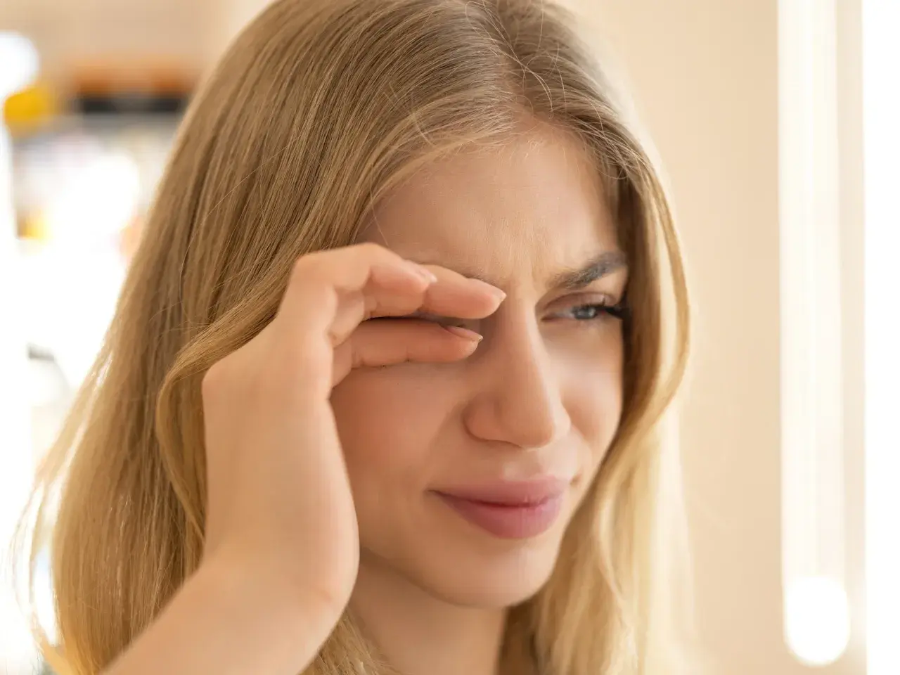 Junge Frau reibt sich die Augen, weil sie flimmern vor den Augen hat. Wahrscheinlich hat sie zu wenig getrunken.