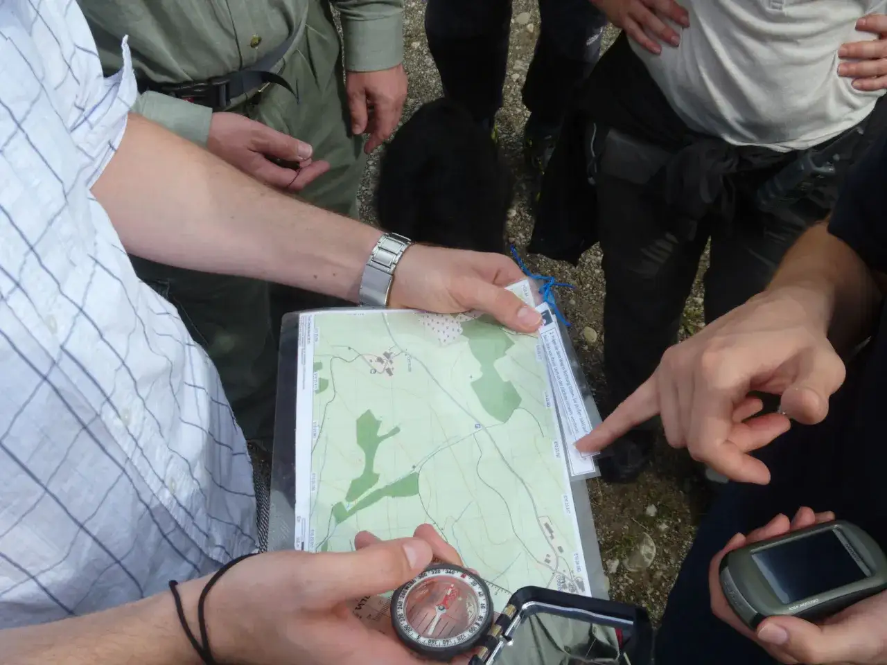 H&auml;nde halten Karte und Kompass, planen die n&auml;chste Etappe eines adventure racing. Ein GPS-Ger&auml;t liegt bereit.