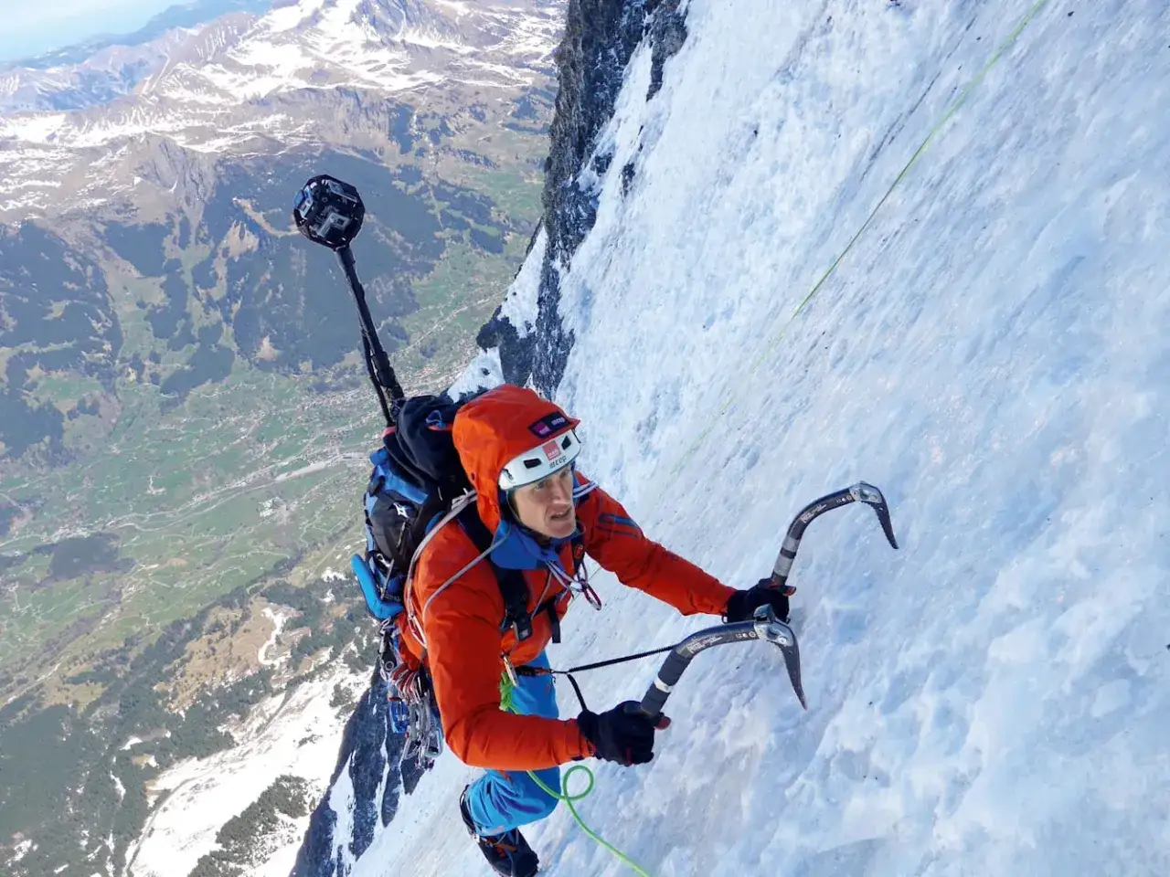 Stephan Siegrist klettert mit Eisger&auml;ten eine steile, eisige Wand empor. Im Hintergrund erstreckt sich ein tiefes Tal.