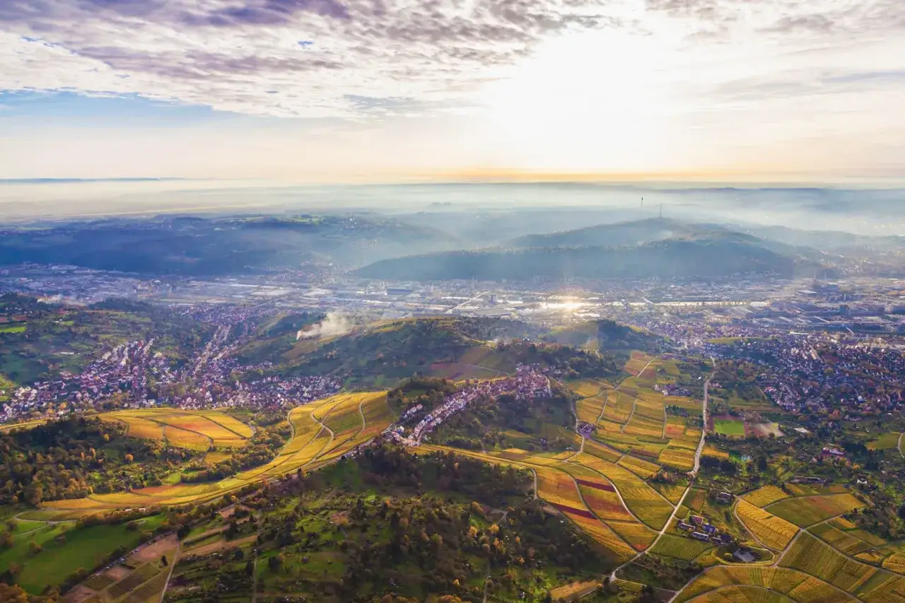 Sonnenuntergang &uuml;ber Stuttgart. Weinberge schl&auml;ngeln sich durch gr&uuml;ne H&uuml;gel, perfekt f&uuml;r eine Wanderung.