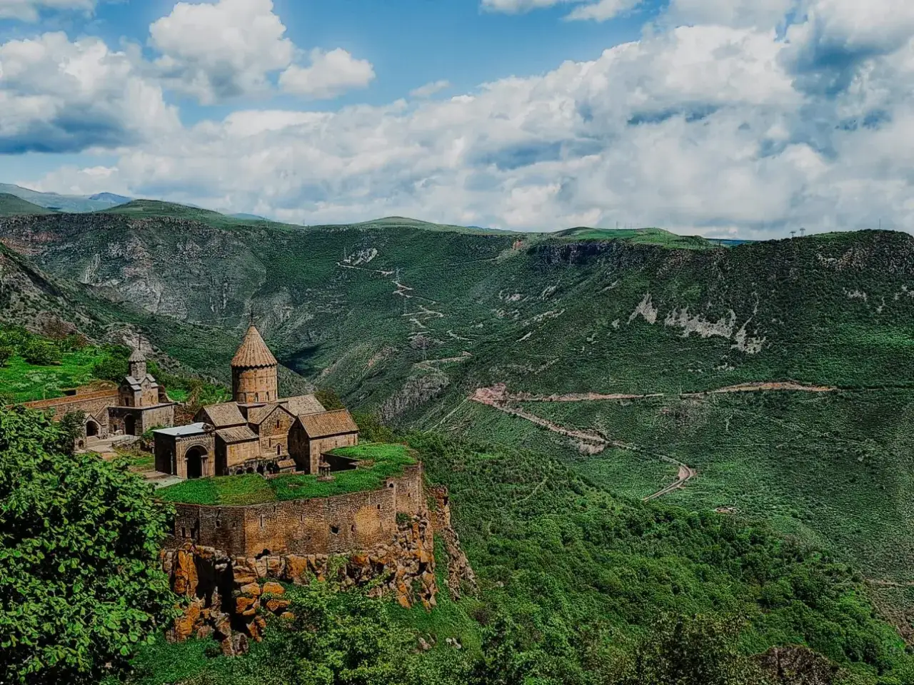 Kloster Tatev thront auf einem Felsvorsprung, umgeben von gr&uuml;nen Bergen. Ein perfekter Ort f&uuml;r Armenien Wanderungen.