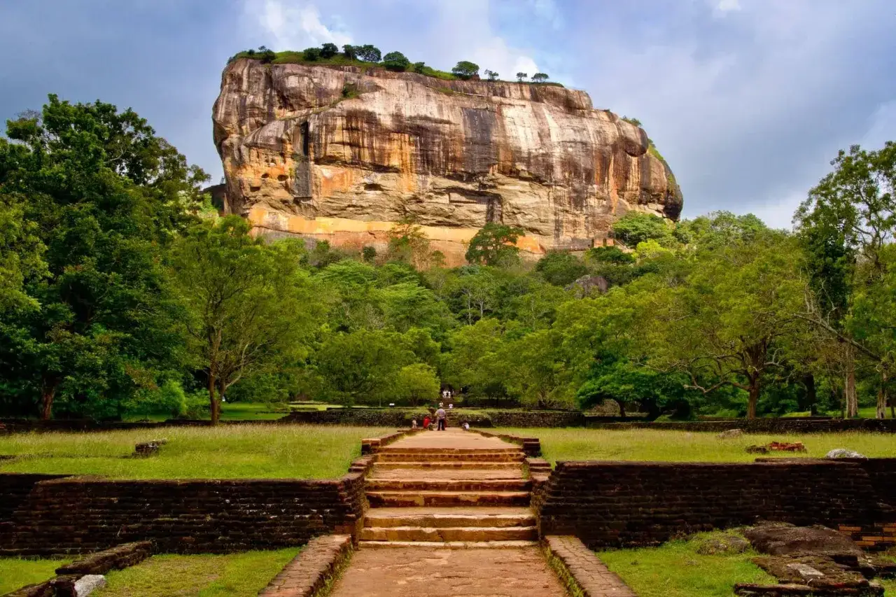 Der majestätische Löwenfelsen, ein absolutes Sri Lanka Must See, ragt über üppige Vegetation. Eine Steintreppe führt zum Eingang.