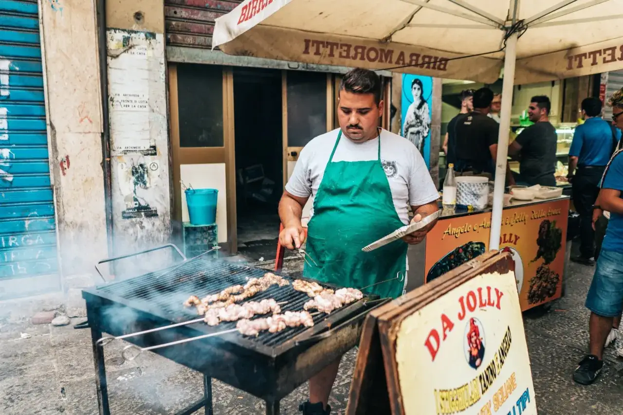 Mann bereitet auf einem Grill k&ouml;stliches Palermo Street Food zu.