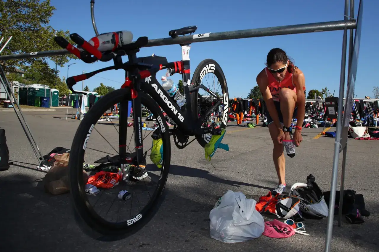 Eine Athletin zieht sich vor dem Rennen um. Ihr Rennrad steht bereit. Die richtige triathlon reihenfolge ist entscheidend.
