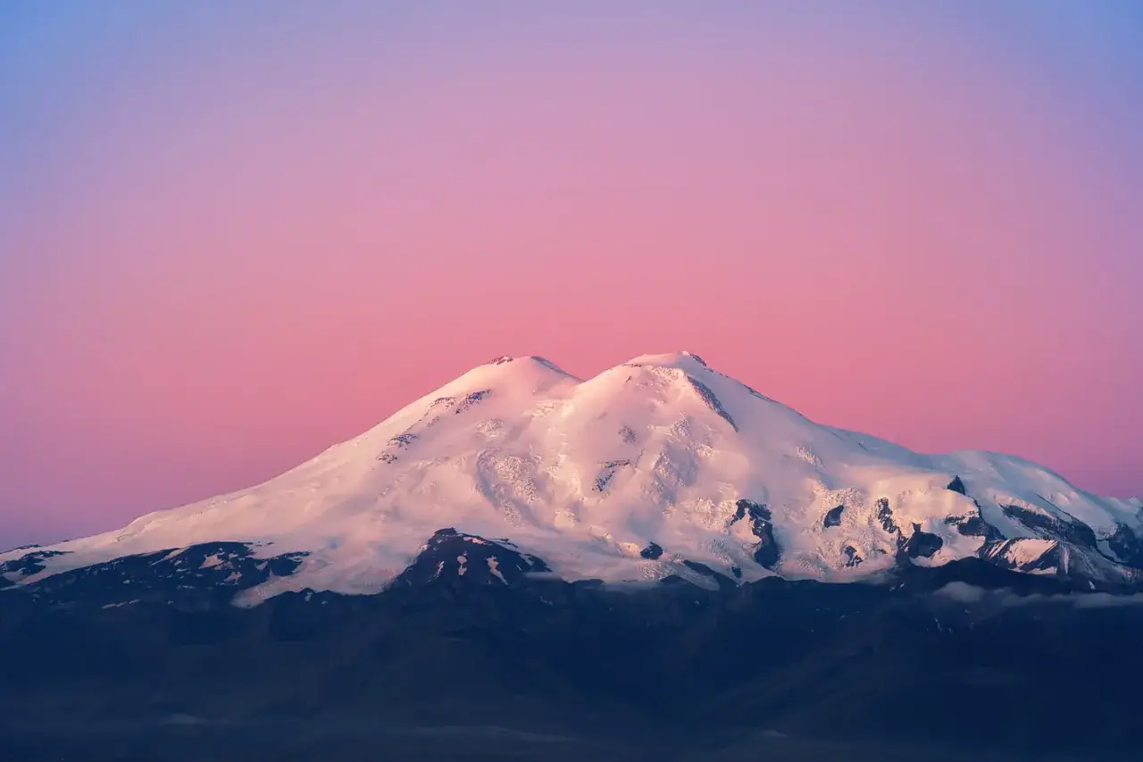 Der Elbrus Berg, bedeckt mit Schnee, ragt majest&auml;tisch in den rosafarbenen Himmel.