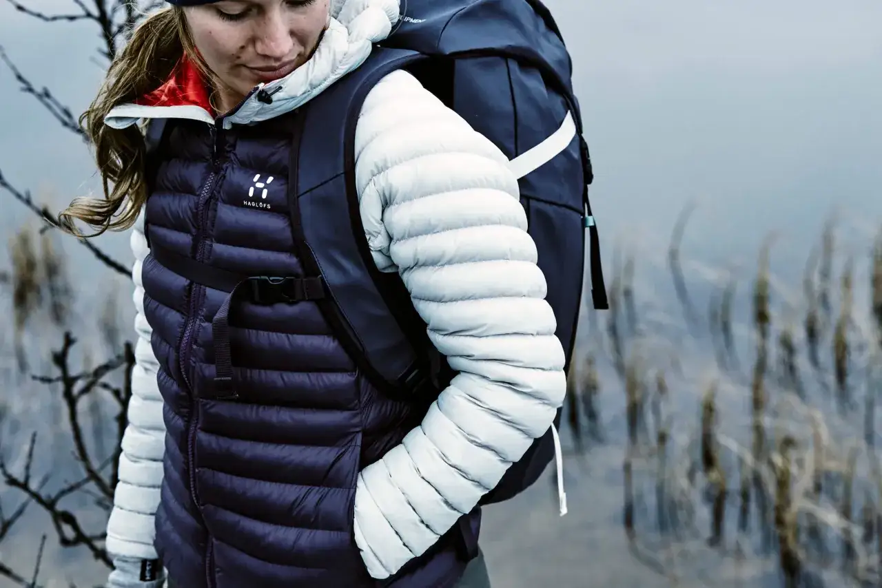 Frau in Daunenjacke und Rucksack, bereit f&uuml;r Abenteuer. Hochwertige norwegische Outdoor-Marken f&uuml;r jeden Trip.