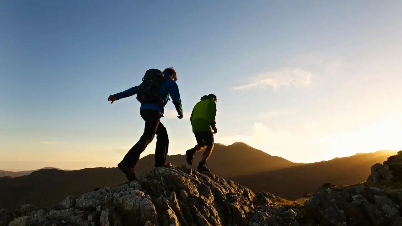 Zwei Wanderer im Abendlicht auf einem felsigen Grat. Ihr Wandern Training f&uuml;hrt sie durch beeindruckende Berglandschaften.