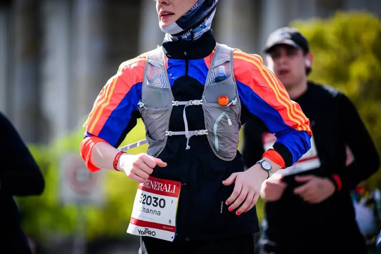 L&auml;uferin mit Startnummer 52030 bei einem Halbmarathon in Essen. Sie tr&auml;gt eine bunte Laufjacke und eine Trinkweste.