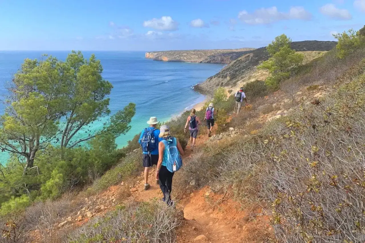 Wanderer genießen die Aussicht auf dem Fischerpfad in Portugal. Türkisfarbenes Meer und eine einsame Bucht säumen den Weg.