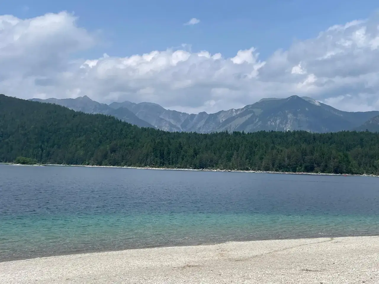 Der Eibsee-Rundweg bietet atemberaubende Ausblicke auf den See, umgeben von dichten Wäldern und majestätischen Bergen unter einem wolkenverhangenen Himmel.