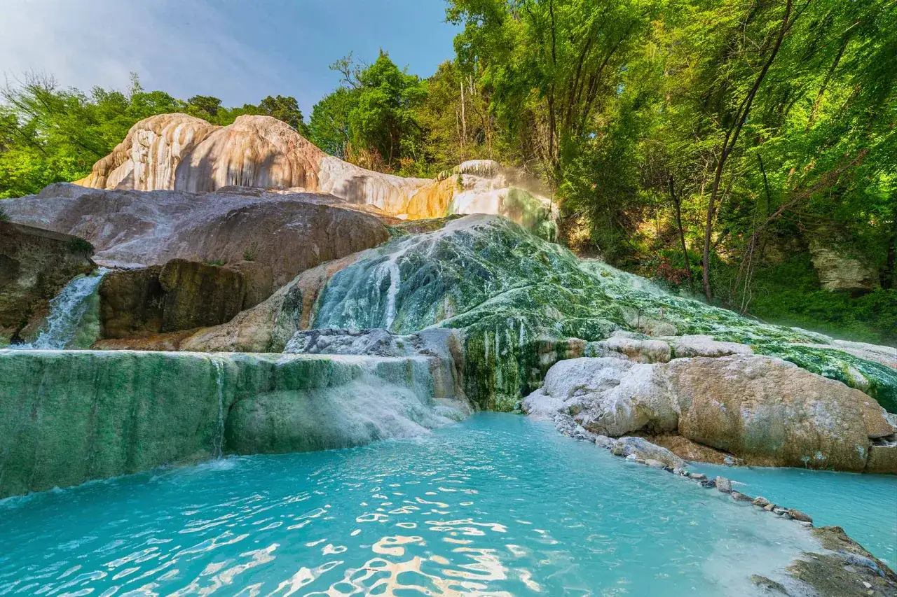 Türkisblaue Becken und terrassierte Wasserfälle, die von mineralischen Ablagerungen überzogen sind, bilden eine natürliche Oase. Die Schwefelquellen Toskana sprudeln hier inmitten üppiger Vegetation.