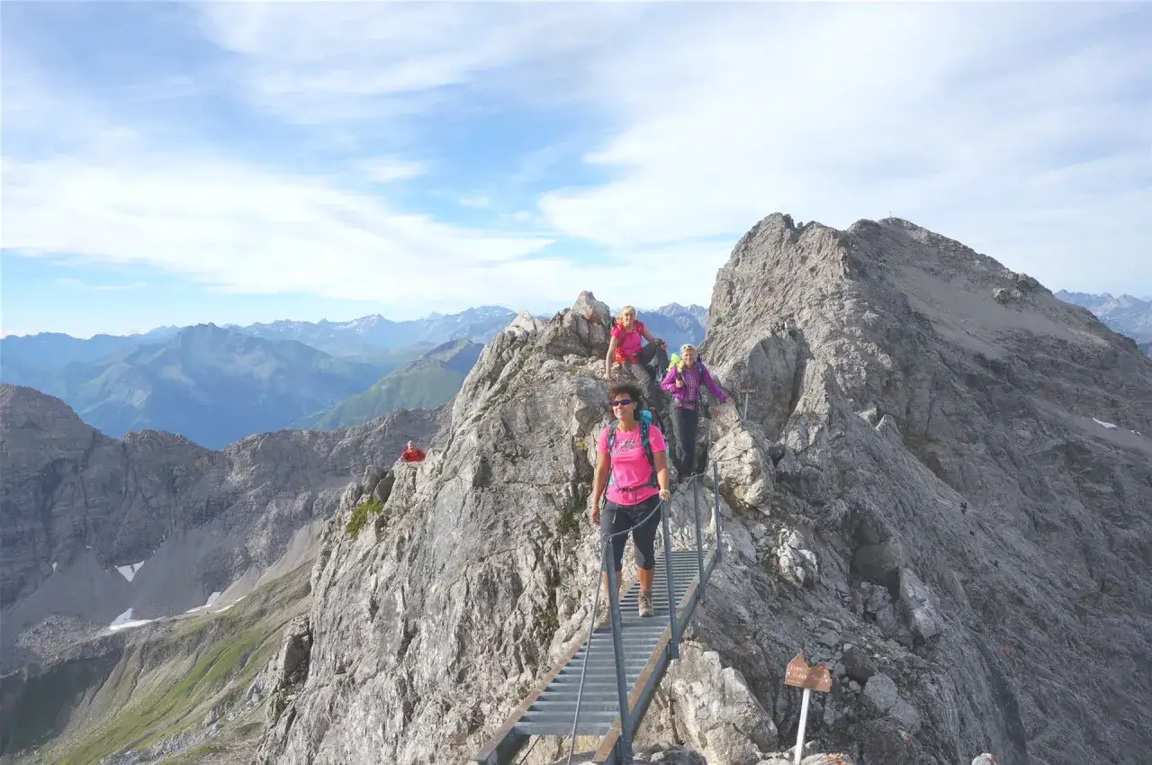 Wanderer auf dem Heilbronner Weg &uuml;berqueren eine Leiterbr&uuml;cke in den Alpen.