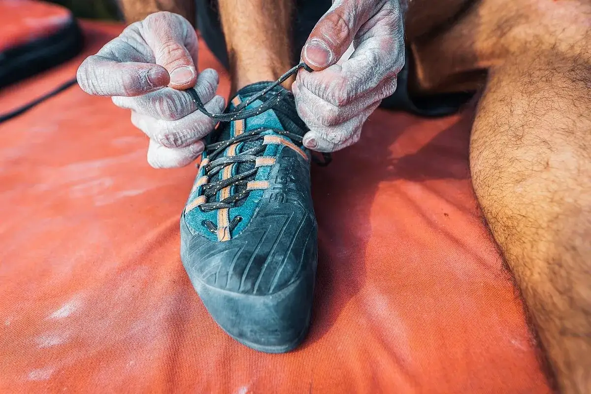 H&auml;nde mit Magnesia binden Kletterschuh. Die richtigen Schuhe f&uuml;r den Klettersteig sind entscheidend f&uuml;r Halt und Komfort.