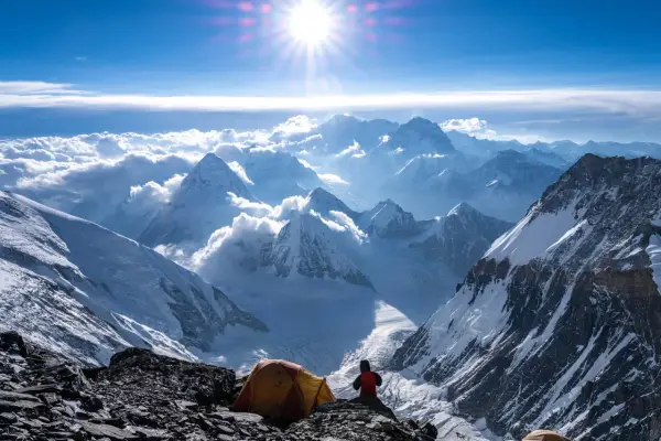 Ein Zeltlager auf dem Weg zum Gipfel des Mount Everest. Die Sonne strahlt über schneebedeckte Berge, Wolken und eisige Täler.